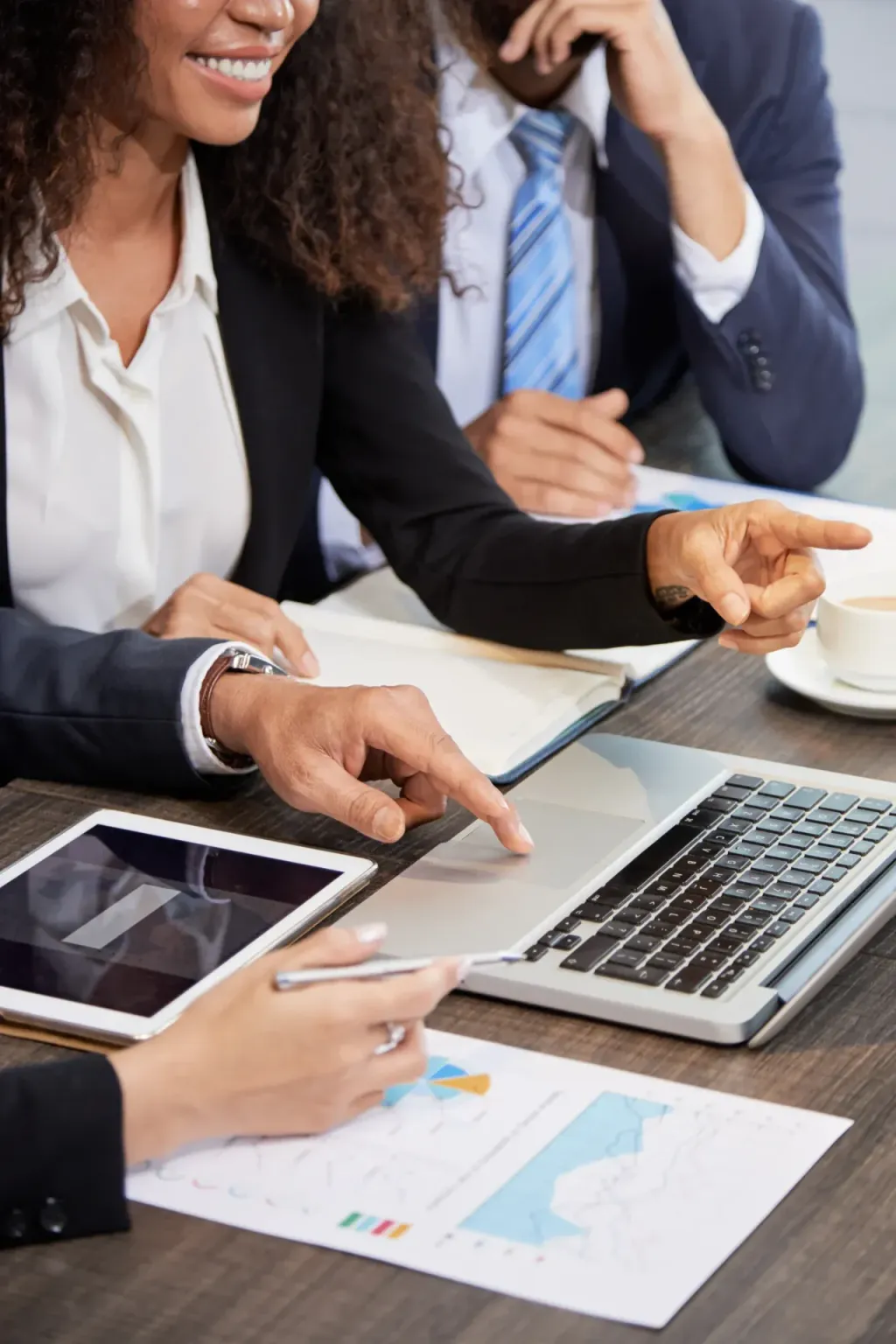 Colleagues pointing at a laptop and tablet during a meeting