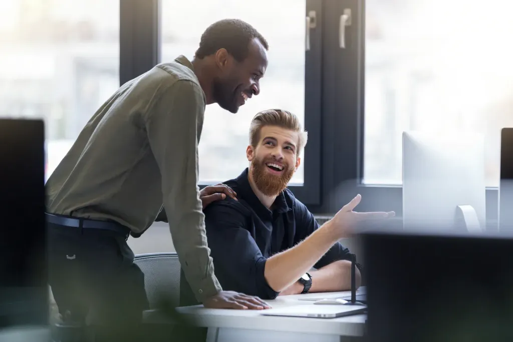 Two colleagues talking at a desk in an office