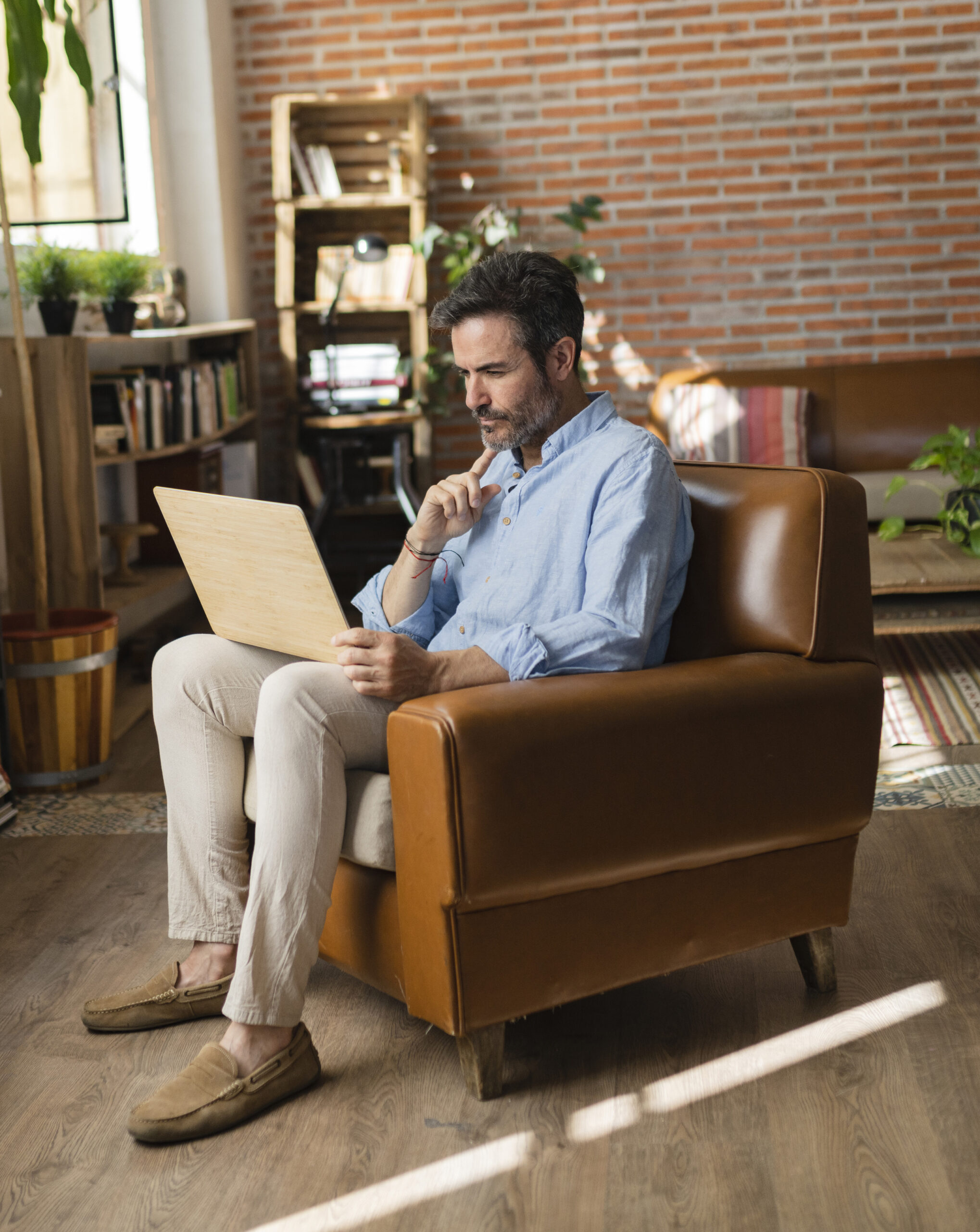 A man engages with his laptop while seated in a leather chair, pondering common 401(k) inquiries.