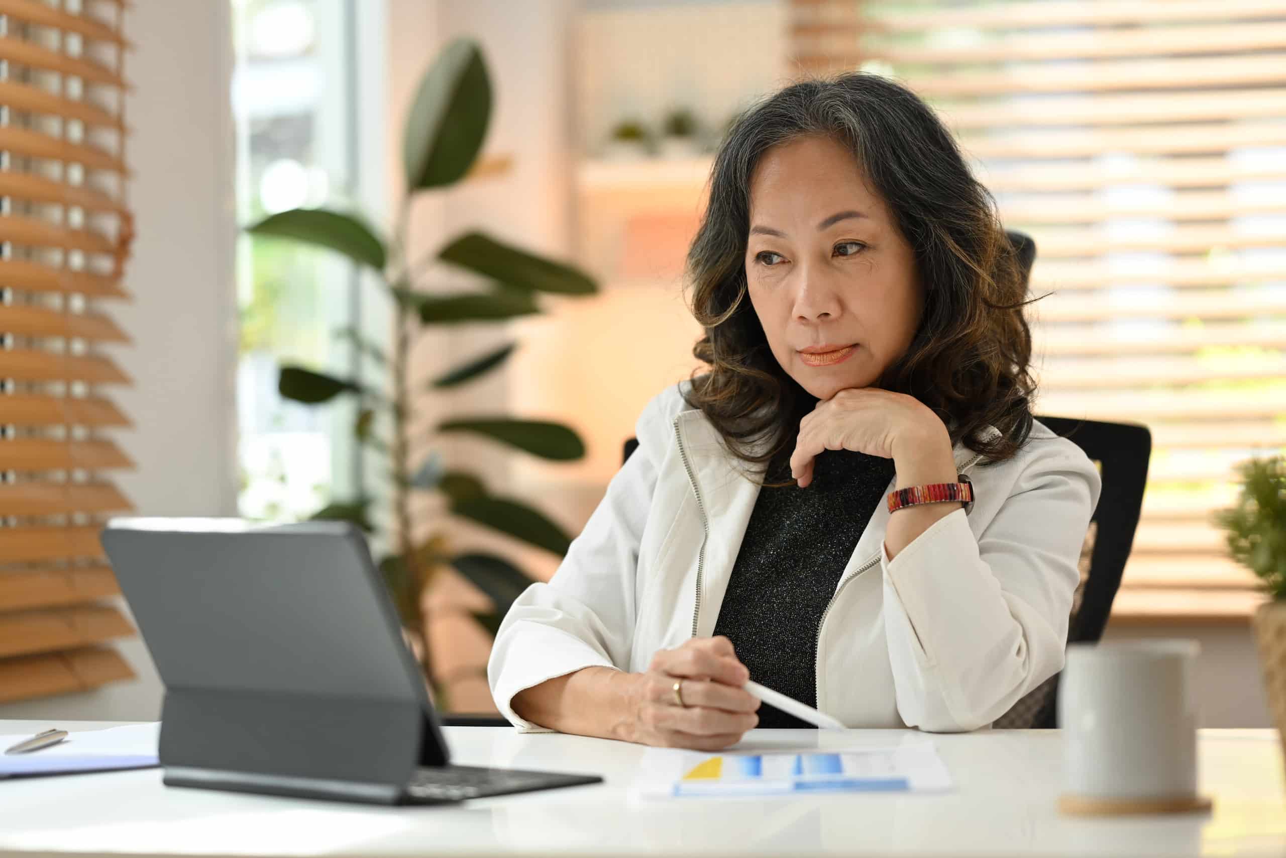 How To Use HB2015 Claims Data to Reduce Healthcare Costs with an asian woman sitting at a desk.