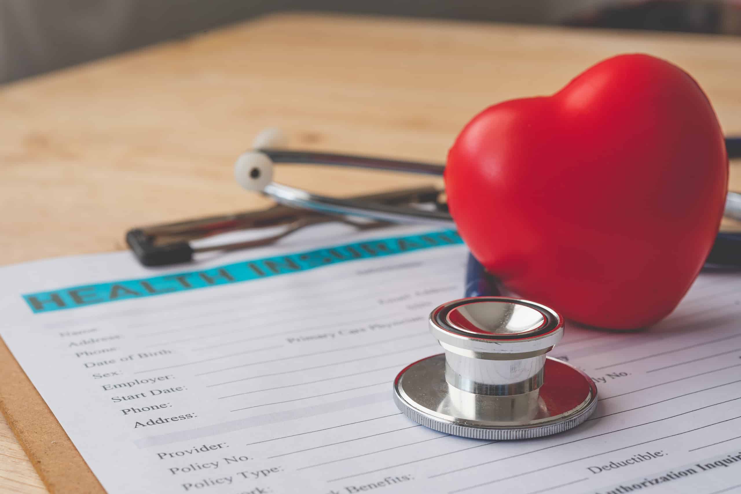 A stethoscope resting on a medical chart with a red heart.