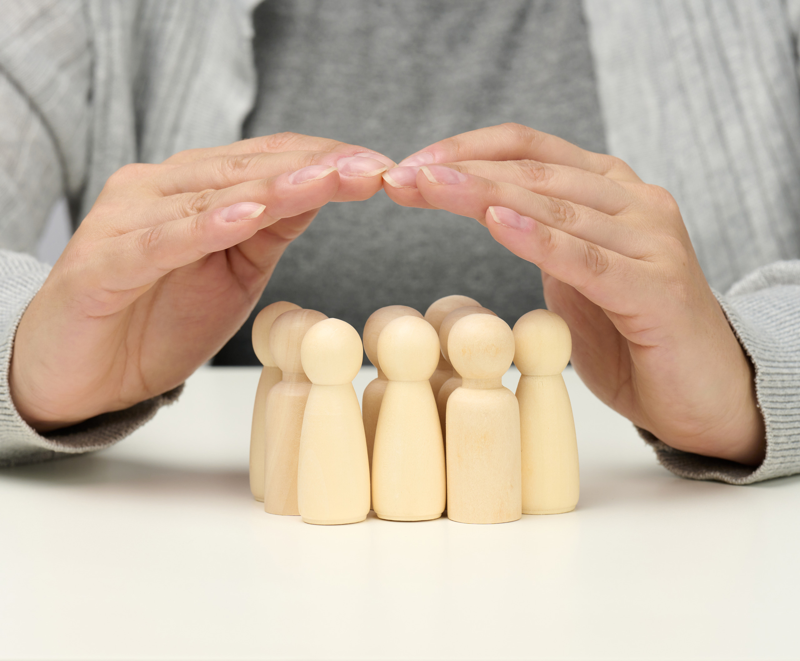 A woman's hands holding a group of wooden figures illustrating the importance of life insurance.