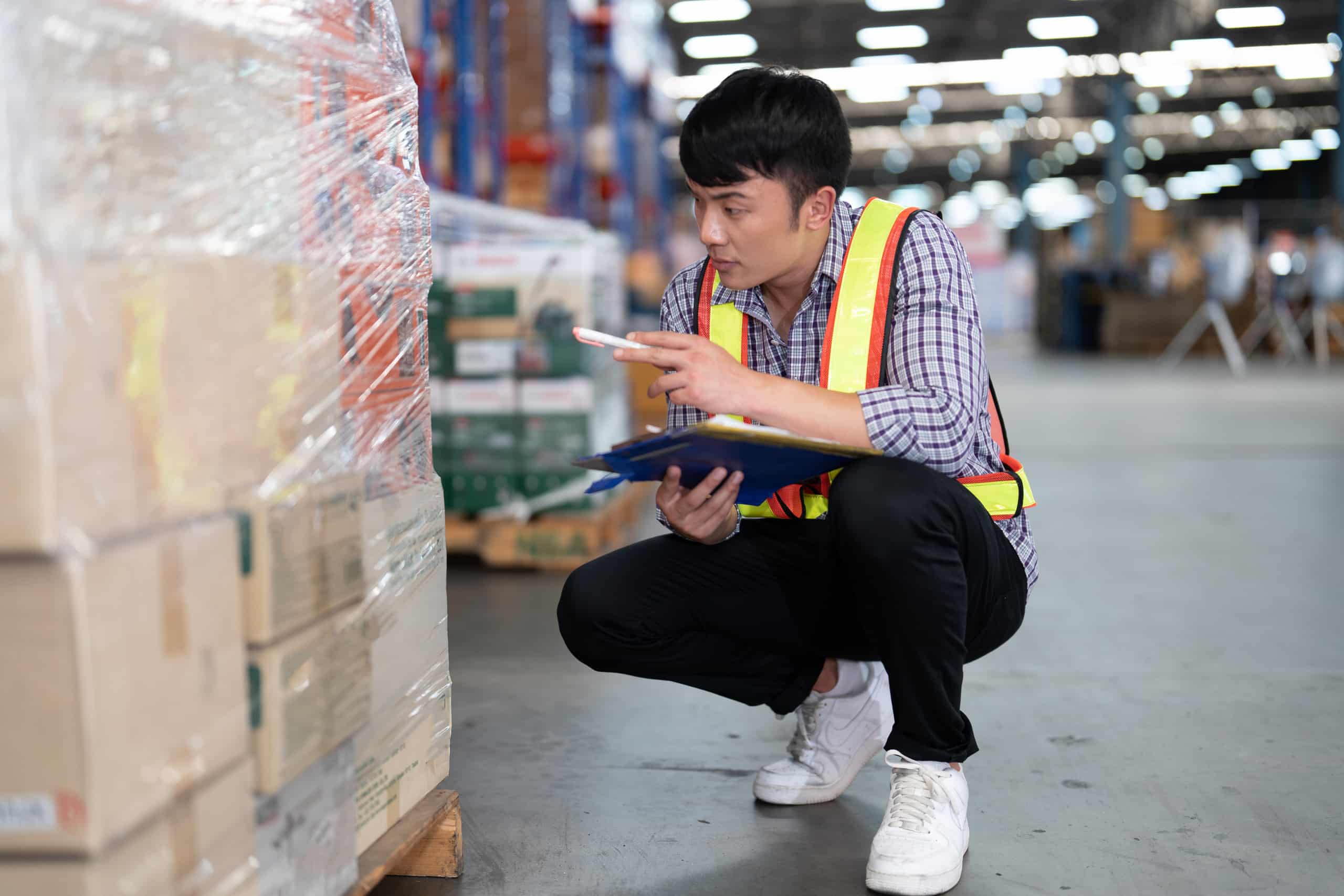 A man in a warehouse holding a clipboard examines the impact of the New Overtime Ruling from the Department of Labor on his business.