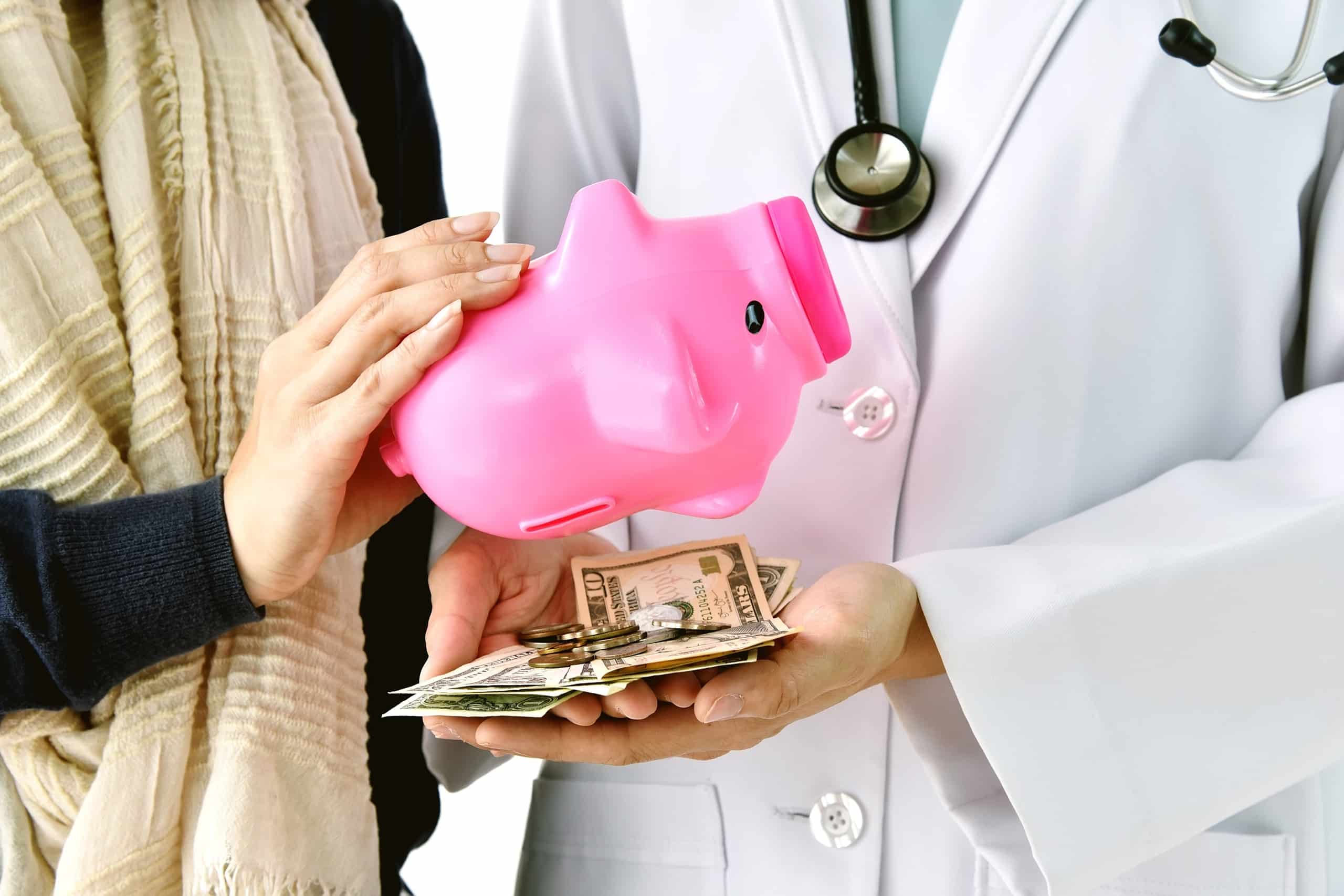 A doctor holding a pink piggy bank and money in a level funded scenario.